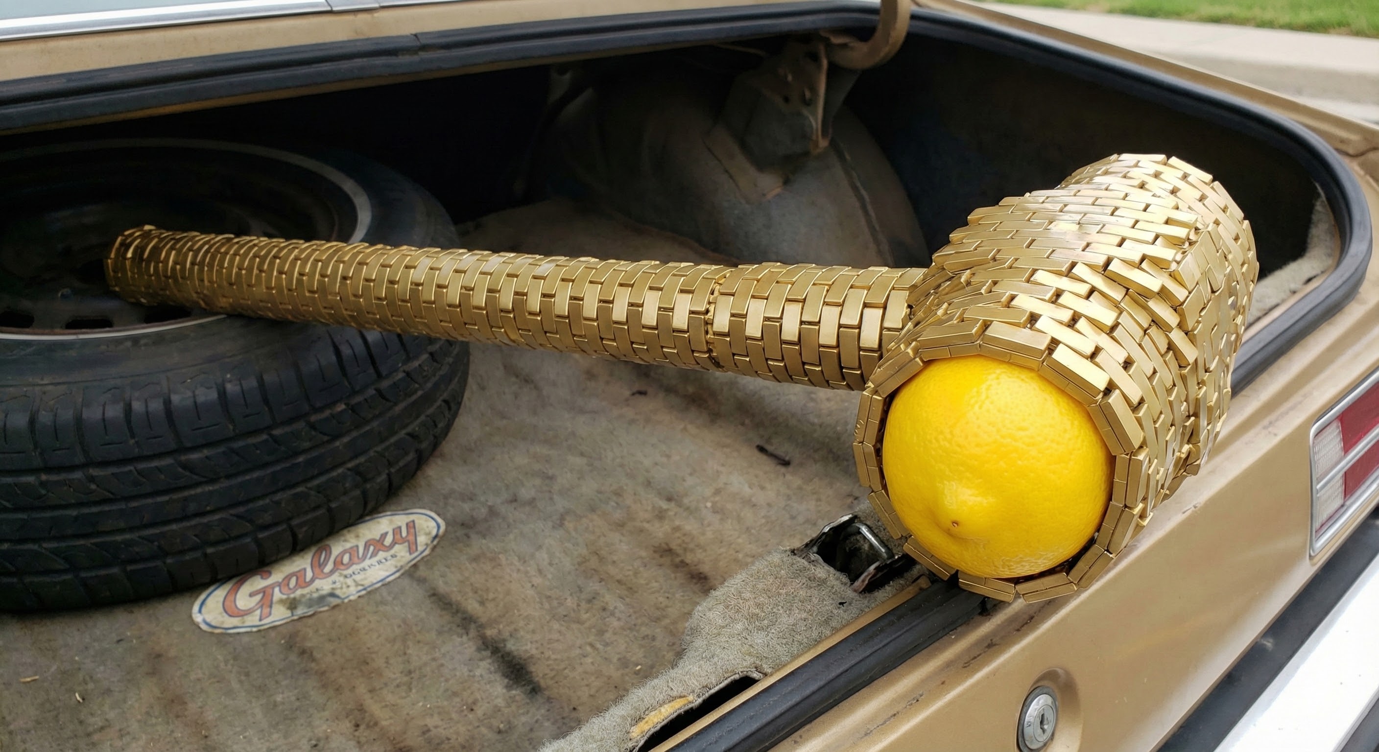 The metaphorical effect: a lemon-tipped croquet mallet with gold wicker weave, resting in the trunk of a Ford Galaxy.